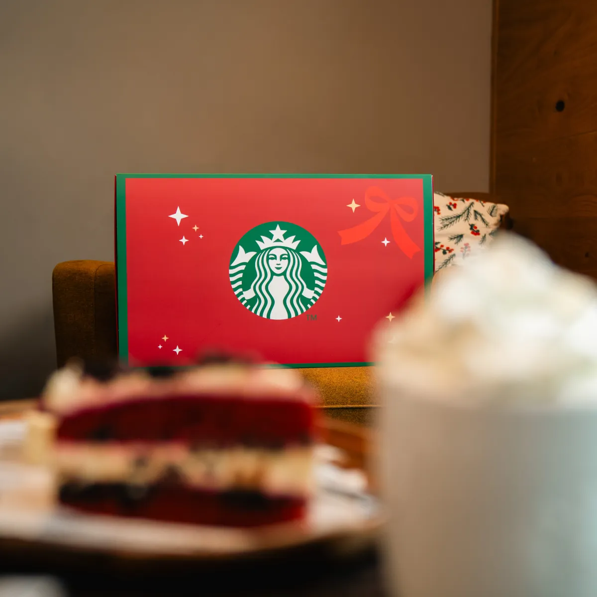 Červený adventný kalendár Starbucks ležiaci na stole s dezertom a kávou