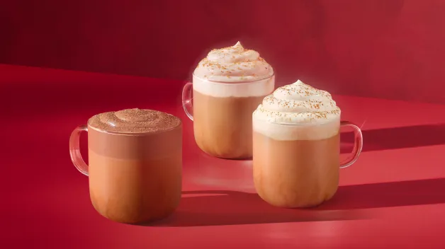 Three drinks with whipped cream in a glass on a red background
