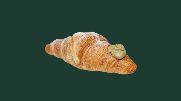 Croissant posypaný práškovým cukrom, s pistáciovým krémom navrchu.