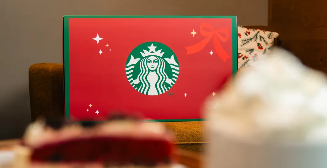 Red Starbucks Advent calendar placed on a table with a drink and dessert