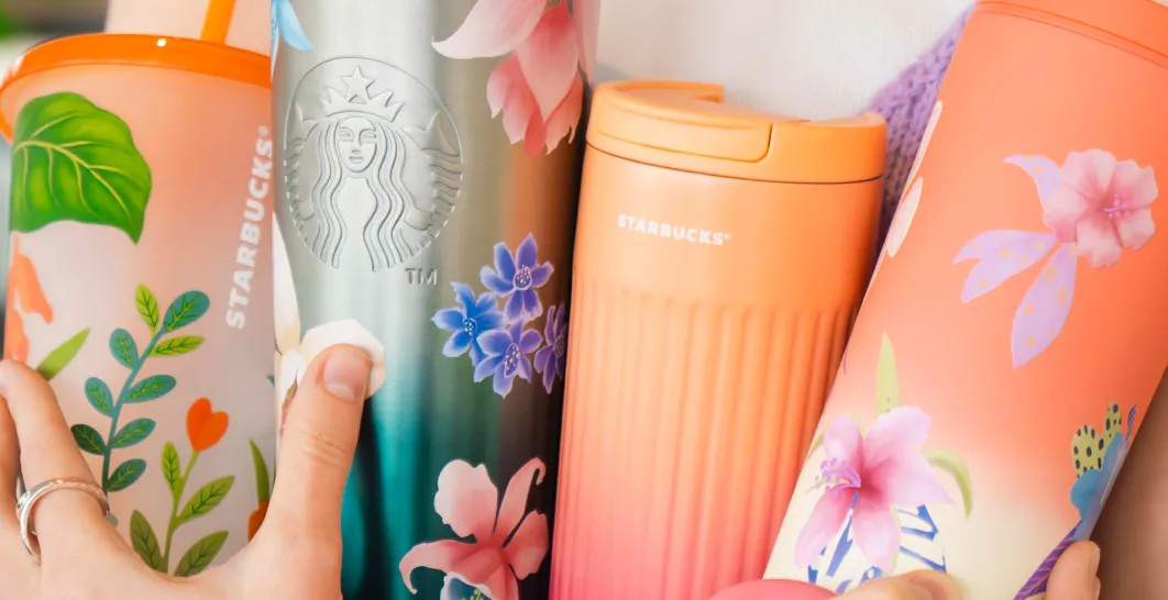 žena drží niekolko designov merche starbucks v rukách